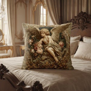 May include: Decorative square pillow featuring a classical painting of an angel with wings, surrounded by roses. The pillow has a detailed, ornate design with a beige and green color palette. The pillow is placed on a bed with a cream-colored comforter.