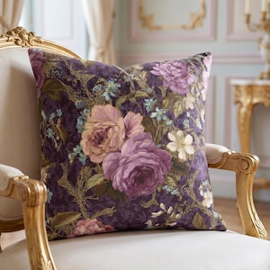 May include: A square throw pillow featuring a deep purple background with a prominent floral pattern of large pink and purple roses, smaller light blue flowers, and white blossoms, accented by intricate gold-colored branch-like line details.