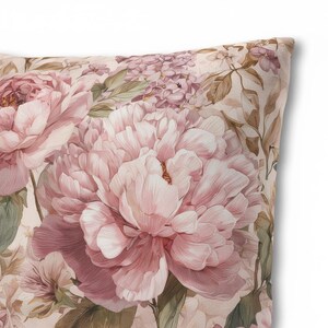 May include: A decorative pillow featuring a watercolor floral design. The pillow showcases large, light pink peonies and other flowers with green leaves against a cream background. The design has a vintage, romantic aesthetic.