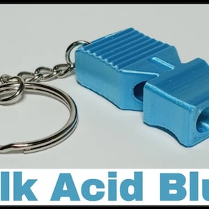 May include: A blue whistle keychain with a silver key ring. The whistle has a textured surface and three holes on the end. The text "Silk Acid Blue" is printed below the image.