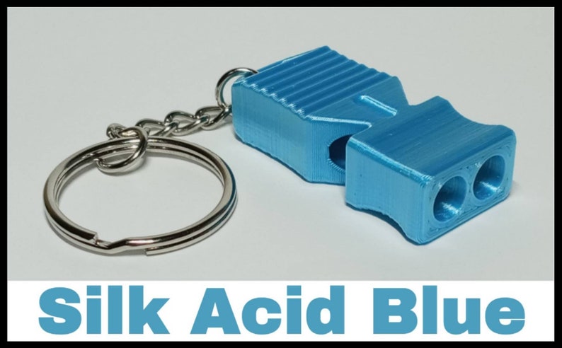 May include: A blue whistle keychain with a silver key ring. The whistle has a textured surface and three holes on the end. The text "Silk Acid Blue" is printed below the image.