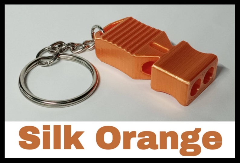 May include: A bright orange whistle with a keychain attached. The whistle has a textured surface and three holes for blowing. The text "Silk Orange" is visible below the image.