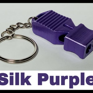 May include: A purple whistle with a silver keychain. The whistle has a textured surface and is made of metal. The keychain is a simple ring.