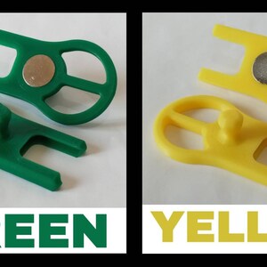 May include: Two plastic tools, one green and one yellow, with a magnet and a small knob. The tools are designed to help with a specific task.