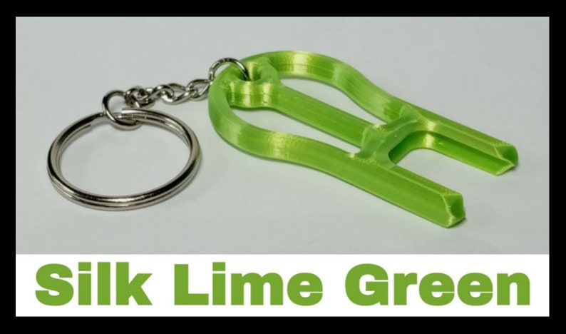 May include: A lime green 3D printed keychain with a key ring. The keychain is shaped like a pair of pliers. The text "Silk Lime Green" is printed below the image.