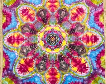 Può includere: Un arazzo mandala colorato con un designo centrale di un fiore multicolore con un motivo geometrico. L'arazzo è fatto di un tessuto morbido e fluido e presenta una varietà di colori, tra cui rosso, giallo, blu, verde e viola.