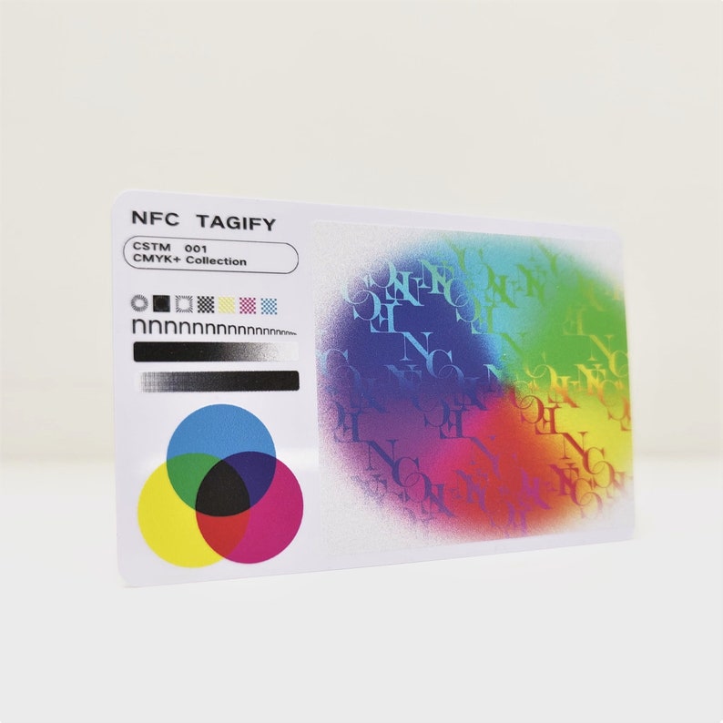 May include: A white card with the text "NFC TAGIFY" and "CSTM 001 CMYK+ Collection" printed on it. The card has a colourful design with a circle of overlapping coloured circles in the centre and a repeating pattern of the letters "NFC" in a rainbow of colours.