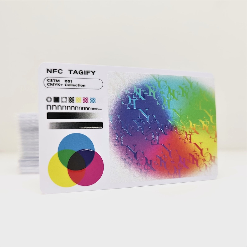May include: A white card with the text "NFC TAGIFY" and "CSTM 031 CMYK+ Collection" printed on it. The card has a colourful design with a rainbow effect and a black, white, yellow, cyan, magenta, and pink colour swatch.
