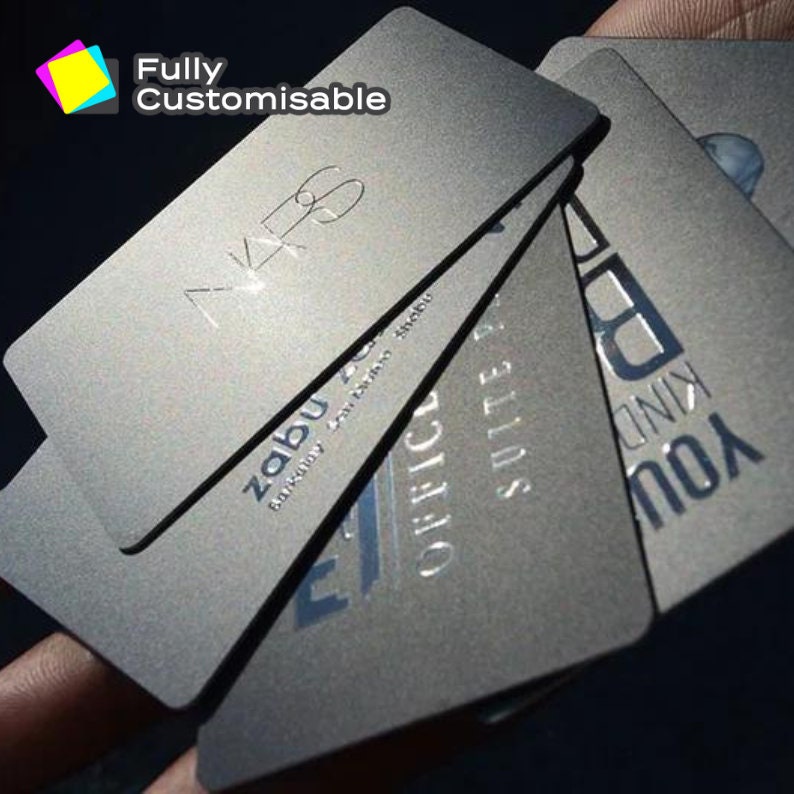May include: A stack of silver metal business cards with embossed text. The top card reads "Fully Customisable" and the text on the other cards is partially visible. The text on the top card is in all caps.