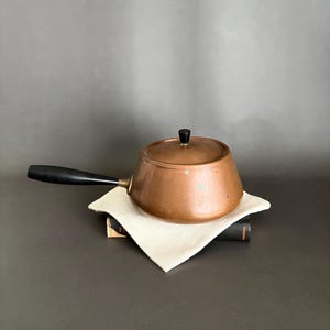 May include: A handmade wooden sign with the text "Welcome" in a whimsical font. The sign is painted white with a distressed finish, and features a decorative floral design in shades of pink and green. It is designed for indoor or outdoor use.