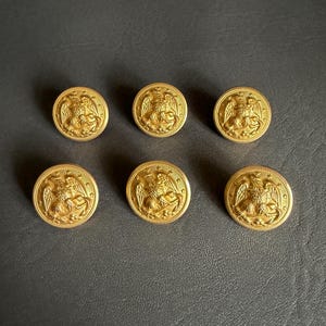 May include: A white ceramic mug with a black handle and the text "But first, coffee" in a black, handwritten-style font. The mug is on a white surface.