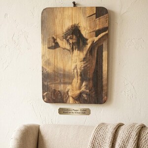 Könnte beinhalten: Eine rechteckige Holztafel mit einem detaillierten geätzten Bild der Kreuzigung Jesu. Unter der Tafel befindet sich ein kleines Metallschild mit der Inschrift: Crucifixion Plaque - Etched Wood Art by JoAnn Clark. Das Kunstwerk ist montiert.
