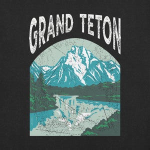 May include: Black graphic featuring the words "GRAND TETON" above a mountain landscape. The design includes a waterfall, trees, and a snow-capped mountain range in shades of blue, green, and white, with a distressed vintage effect.