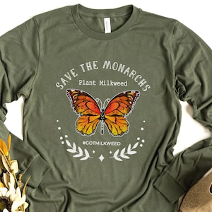 K&ouml;nnte beinhalten: Ein gr&uuml;nes Langarmshirt mit einer wei&szlig;en Grafik eines Monarchfalters und dem Text "Save the Monarchs Plant Milkweed #GotMilkweed".