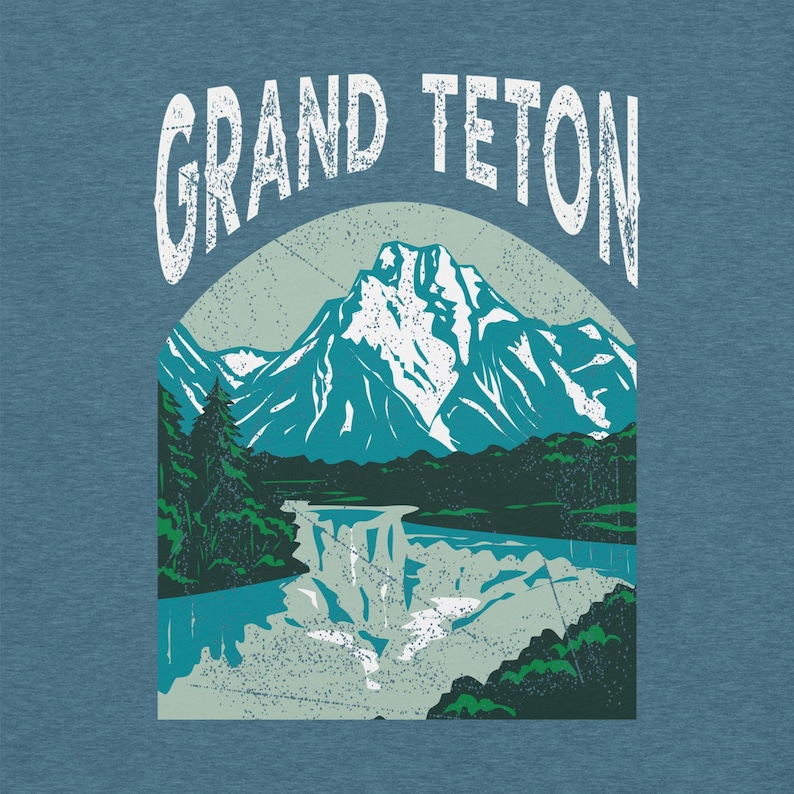 May include: A blue t-shirt featuring a graphic of the Grand Teton mountain range. The design includes a mountain with snow-capped peaks, a waterfall, and the text "GRAND TETON" in a distressed font.