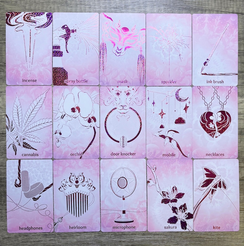 May include: A set of 15 pink and white cards with illustrations of various objects, including incense, a spray bottle, a mask, a sprinkler, an ink brush, cannabis, an orchid, a door knocker, a mobile, a necklace, headphones, a heirloom, a microphone, a sakura flower, and a kite. Each card has the name of the object written below the illustration.
