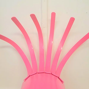May include: A pink chair with a unique design featuring multiple curved, thin, pink metal rods extending upwards from the seat.
