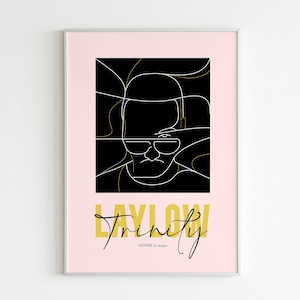 May include: A black and white line art illustration of a person's face with a gold background. The text "Laylow Trinity" is written in gold letters below the illustration. The text "ARTWORK by noopic" is written in black letters below the gold text.