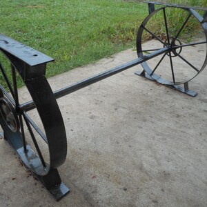 May include: A black metal table with two round wheels as legs. The table is made of sturdy metal and has a simple design.