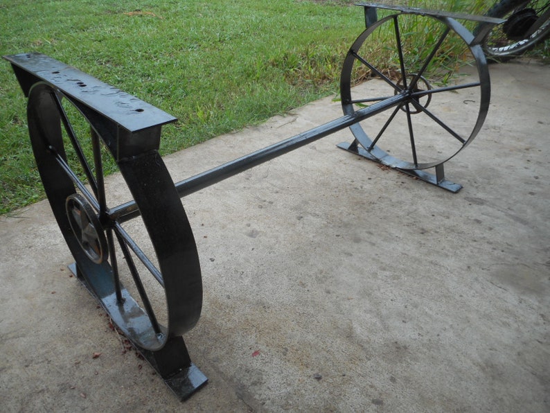 May include: A black metal table with two round wheels as legs. The table is made of sturdy metal and has a simple design.