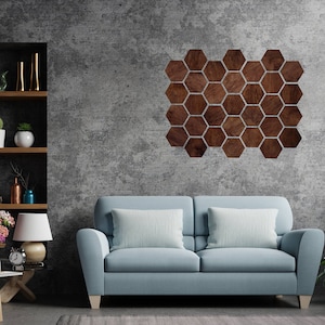 May include: A light blue sofa with two white cushions sits in front of a grey concrete wall with a geometric wooden wall art piece in the shape of hexagons.