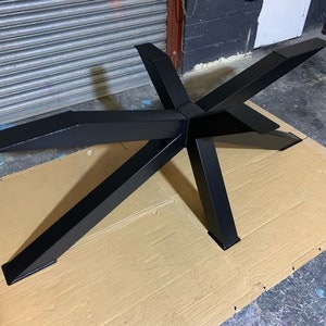 May include: Black metal table base with a starburst design. The base is made of thick metal and has a smooth, matte finish.