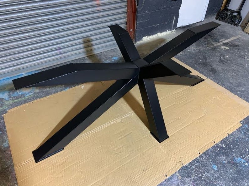 May include: Black metal table base with a starburst design. The base is made of thick metal and has a smooth, matte finish.