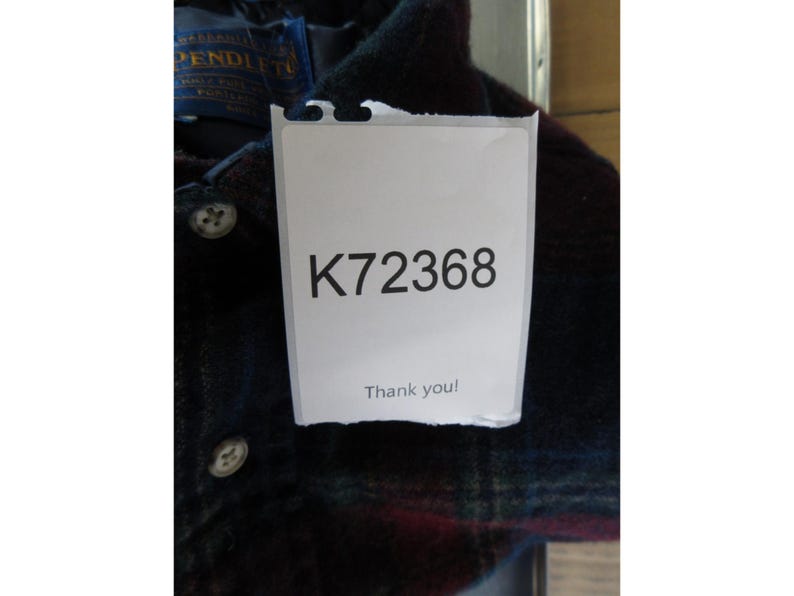 May include: A dark plaid button-down shirt featuring a Pendleton brand label at the collar. A white rectangular tag is attached to the front, displaying the alphanumeric code K72368 and the text Thank you! in black ink.