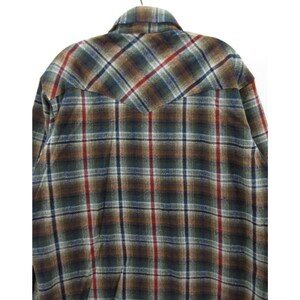 May include: A long-sleeved button-up shirt featuring a plaid pattern in shades of brown, dark green, blue, and red. The shirt has a pointed western-style back yoke and a standard collar, showcasing a textured fabric finish throughout the garment.