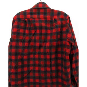 Puede incluir: Una camisa de manga larga con botones que presenta un patr&oacute;n de cuadros cl&aacute;sico en rojo y negro. La prenda tiene un cuello est&aacute;ndar, un canes&uacute; en la espalda y un cierre frontal de botones, con un dise&ntilde;o de cuadros uniforme en toda la tela.