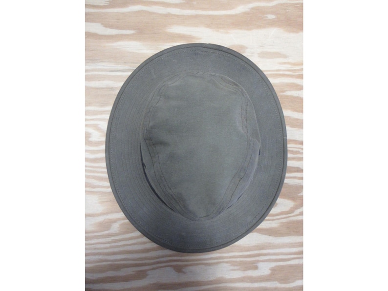 Op de afbeelding: Een grijze hoed met brede rand en een ronde kroon. De hoed is gemaakt van een duurzame stof en heeft een eenvoudig, klassiek ontwerp. De rand van de hoed is ongeveer 7.6 cm breed. Deze hoed is geschikt voor buitenactiviteiten.