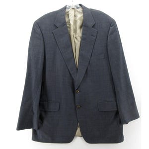 Peut inclure: Un blazer gris foncé avec une fermeture à bouton unique et deux poches. Le blazer a un motif subtil et un tissu doux et texturé.