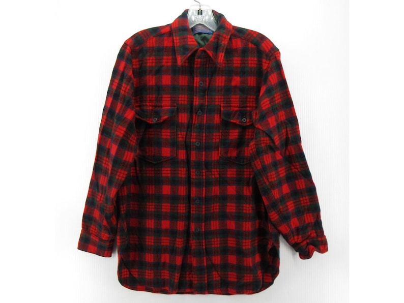 Puede incluir: Una camisa de manga larga con botones y un patr&oacute;n de cuadros rojos y negros. La camisa incluye un cuello est&aacute;ndar, una tapeta frontal con botones y dos bolsillos en el pecho con solapas abotonadas. Los pu&ntilde;os tambi&eacute;n tienen botones.
