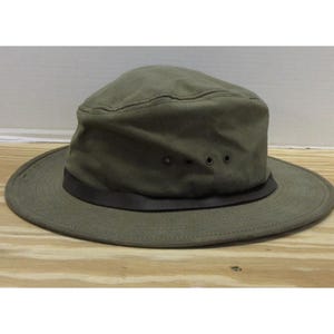 Op de afbeelding: Olijfgroene hoed met een brede rand en een donkerbruine band. De hoed heeft een gestructureerde kroon met drie kleine ventilatiegaten. Gemaakt van duurzame stof, geschikt voor buitenactiviteiten.