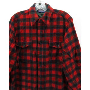 Puede incluir: Una camisa de manga larga con botones y un patr&oacute;n de cuadros rojos y negros. La camisa incluye un cuello puntiagudo, una tapeta central con botones y dos bolsillos en el pecho con solapas abotonadas. La tela tiene una textura suave y cepillada.