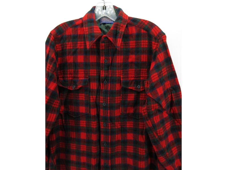 Puede incluir: Una camisa de manga larga con botones y un patr&oacute;n de cuadros rojos y negros. La camisa incluye un cuello puntiagudo, una tapeta central con botones y dos bolsillos en el pecho con solapas abotonadas. La tela tiene una textura suave y cepillada.