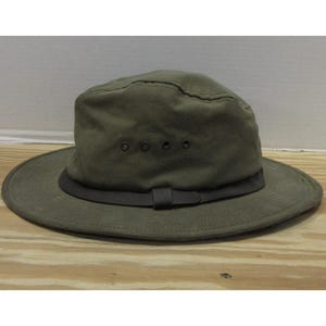 Op de afbeelding: Olijfgroene hoed met een brede rand en een donkerbruine band. De hoed heeft een gestructureerde kroon met ventilatie-ogen. Een casual outdoor accessoire.