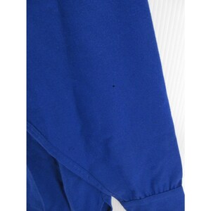 May include: A long-sleeved shirt in a solid, vibrant royal blue color. The garment features a smooth, opaque fabric texture with a visible cuff at the end of the sleeve and a small, dark spot imperfection on the upper portion of the fabric.
