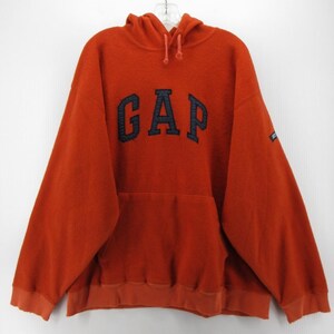 May include: An orange hooded sweatshirt featuring the navy blue word "GAP" across the chest. It has a kangaroo pocket and a drawstring hood. The cuffs and hem are ribbed.