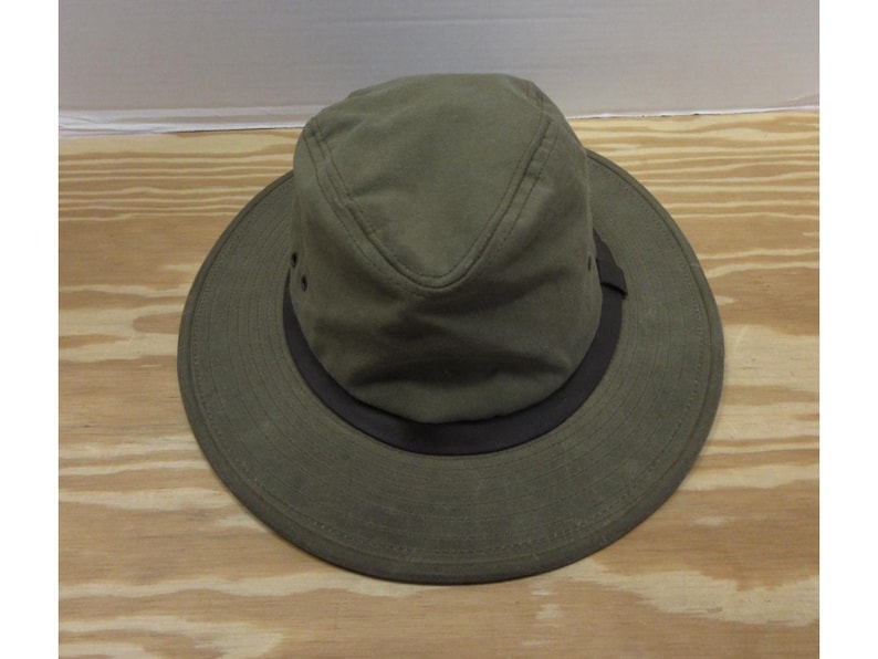 Op de afbeelding: Olijfgroene hoed met een brede rand en een donkerbruine band. De hoed heeft een gestructureerde kroon en kleine ventilatiegaten. Gemaakt van duurzame stof, geschikt voor buitenactiviteiten.