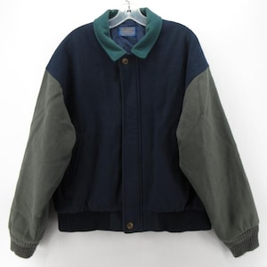 May include: A navy blue jacket with green sleeves and a green collar. The jacket has a button closure and a ribbed hem and cuffs. The jacket is hanging on a white background.