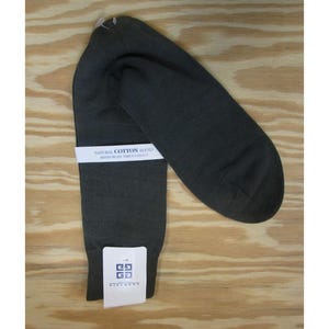 May include: Dark grey socks with a white label reading "NATURAL COTTON BLEND" and a logo. The socks are folded on a light brown wooden surface. The socks are made of a natural cotton blend.
