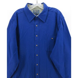 May include: A long-sleeved button-down shirt in a vibrant royal blue color. The shirt features a classic collar, a single chest pocket on the left side, and light-colored buttons down the front placket. The interior collar lining is a light gray.