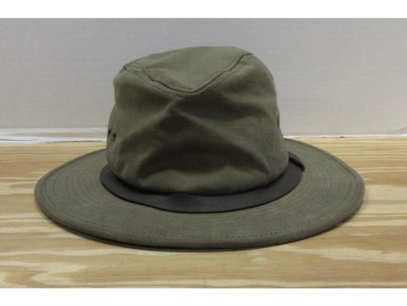 Op de afbeelding: Olijfgroene hoed met een brede rand en een donkerbruine band. De hoed heeft een gestructureerde kroon en lijkt gemaakt te zijn van een duurzame stof. Een praktisch accessoire voor bescherming tegen de zon en buitenactiviteiten.