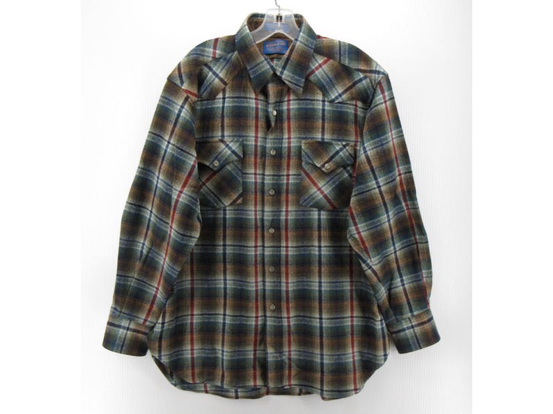 May include: A long-sleeve button-down shirt featuring a plaid pattern in shades of dark green, brown, blue, and red. The shirt includes a pointed collar, two chest pockets with buttoned flaps, and a front button closure with matching buttons.