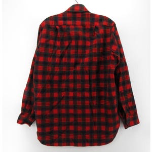 Puede incluir: Una camisa de manga larga con botones y un llamativo patr&oacute;n de cuadros rojos y negros. La prenda incluye un cuello est&aacute;ndar, un bolsillo en el pecho en el lado izquierdo y pu&ntilde;os abotonados, mostrada desde una perspectiva trasera.