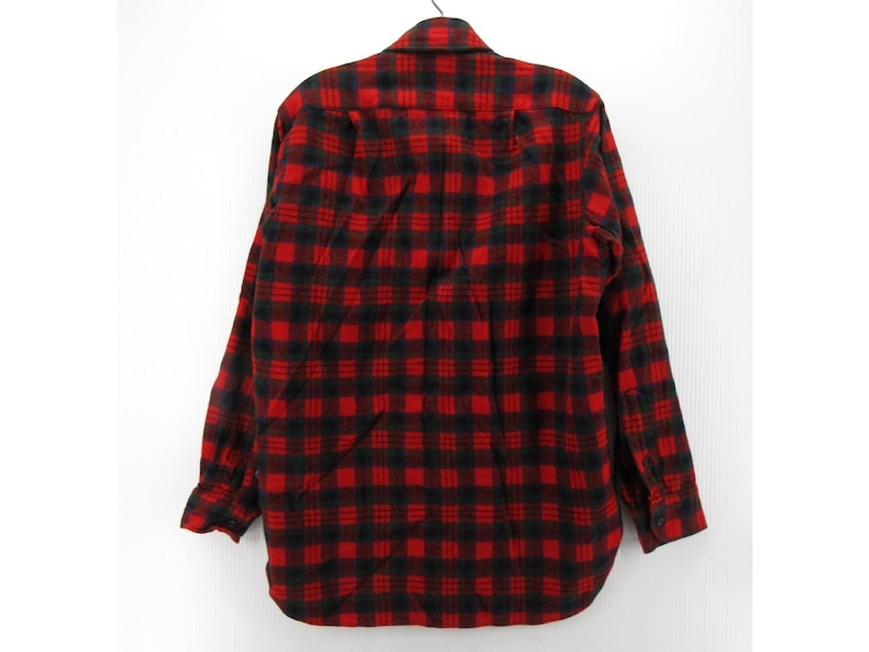 Puede incluir: Una camisa de manga larga con botones y un llamativo patr&oacute;n de cuadros rojos y negros. La prenda incluye un cuello est&aacute;ndar, un bolsillo en el pecho en el lado izquierdo y pu&ntilde;os abotonados, mostrada desde una perspectiva trasera.