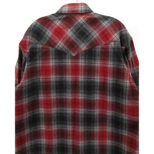 May include: A long-sleeve button-up shirt featuring a red, black, and grey plaid pattern. The garment includes a pointed back yoke design, a standard collar, and a textured fabric finish, showcasing a consistent checkered print throughout the back.