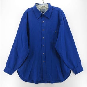 May include: A long-sleeve button-down shirt in a solid royal blue color. The shirt features a classic collar, a single chest pocket on the left side, and a full-length front button placket with matching blue buttons. The interior collar lining is light gray.