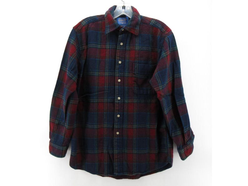 May include: A long-sleeve button-down shirt featuring a dark navy blue, deep red, and forest green plaid pattern. The shirt includes a standard collar, a single chest pocket on the left side, and light-colored buttons running down the front placket.